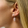 A model wearing Juraster's Sterling Silver Rose Quartz Stud Earring, Adventure, crafted from Fairmined sterling silver and hand-cut rose quartz, with a matching earring charm attached.