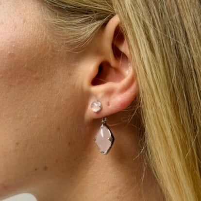 A model wearing Juraster's Sterling Silver Rose Quartz Stud Earring, Adventure, crafted from Fairmined sterling silver and hand-cut rose quartz, with a matching earring charm attached.