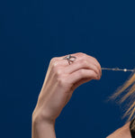 A model wearing Juraster’s Sterling Silver Diamond-Shape Ring, Compass, crafted from Fairmined sterling silver.  She also wears a white gold pavé diamond diamond-shaped ring and a sterling silver pearl bracelet. 