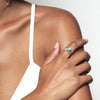 A model wearing Juraster’s 9ct Gold Stacking Ring in Persian Blue Turquoise, Lodestone, crafted from Fairmined 9ct yellow gold and a hand-cut turquoise gemstone, alongside a yellow gold chrysoprase ring.