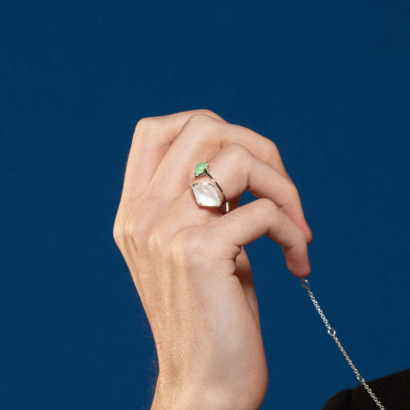 A model wearing Juraster’s 9ct White Gold Rainbow Moonstone Ring, Talisman, crafted from Fairmined 9ct white gold and a hand-cut moonstone. He also wears a white gold chrysoprase ring and a sterling silver necklace chain.