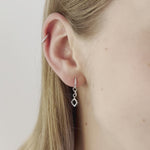 A video of a model wearing Juraster’s Sterling Silver Diamond-Shaped Earring Charm, Compass, crafted from Fairmined sterling silver, attached to a sterling silver hoop, along with a sterling silver hoop in her cartilage.